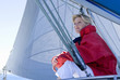 Photo: Woman in red jacket sitting on deck of sailing boat below sail, daydreaming, side view, low angle view Woman in red jacket sitting on deck of sailing boat below sail, daydreaming, side view, low angle view