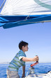 Photo: Boy (8-10) winding rope pulley of boat rigging on deck of sailing boat out at sea, profile Boy (8-10) winding rope pulley of boat rigging on deck of sailing boat out at sea, profile
