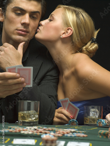 Photo: Woman kissing man's cheek at poker game Woman kissing man's cheek at poker game