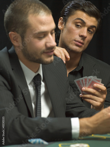 Photo: Man looking over man's shoulder during poker game Man looking over man's shoulder during poker game