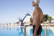 A young man standing by a swimming pool