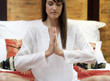 A woman sitting on a bed meditating
