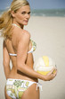 A young woman on a beach holding a ball