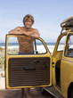 A young man leaning on the door of a car