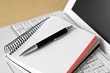 A laptop, a notebook and a pen on a desk. 