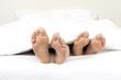Close-up of feet of couple in bed