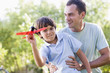 Man and young boy outdoors playing with toy airplane 