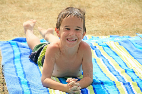 boy laying on beach towel