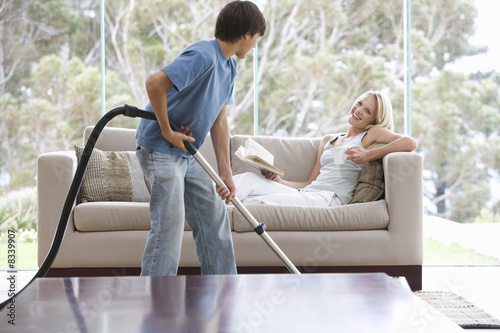 Photo: A young boy vacuuming whilst his mother relaxes A young boy vacuuming whilst his mother relaxes