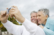 Foto: A senior couple on a beach taking a picture with a digital camera A senior couple on a beach taking a picture with a digital camera