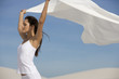 A young woman standing in the desert with a sheet