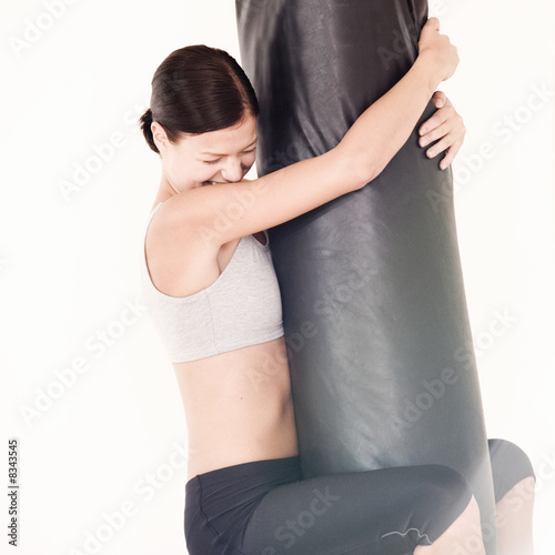 Photo: A young woman hugging a punch bag A young woman hugging a punch bag