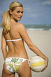 A young woman on a beach holding a ball