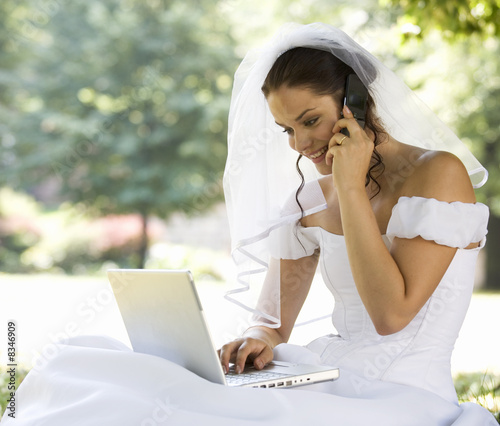 Photo: A bride using a laptop and mobile phone A bride using a laptop and mobile phone