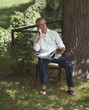 Man talking on a mobile phone, sitting next to a tree