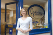 Woman standing at front entrance of optometrists smiling