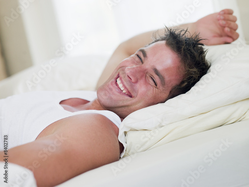 Photo: Man lying in bed laughing Man lying in bed laughing