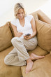 Woman in living room using personal digital assistant smiling