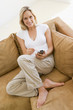 Woman in living room using personal digital assistant smiling
