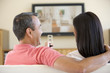 Couple in living room watching television laughing