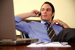 Young businessman sitting at desk and talking on cell phone