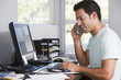 Man in home office on telephone using computer and smiling Man in home office on telephone using computer and smiling