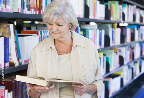 Photo: Senior woman reading in a library Senior woman reading in a library
