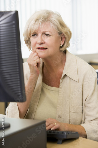 Photo: Confused woman frowning at computer monitor Confused woman frowning at computer monitor