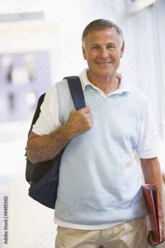 Photo: A man with a backpack standing in a campus corridor A man with a backpack standing in a campus corridor