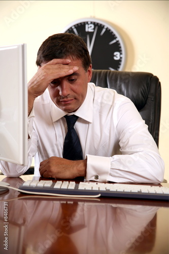 Photo: Businessman sitting at his desk lost in thought Businessman sitting at his desk lost in thought