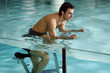Young man on exercise bike in spa pool