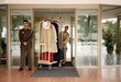 Bellboy delivering luggage to hotel with doorman standing by