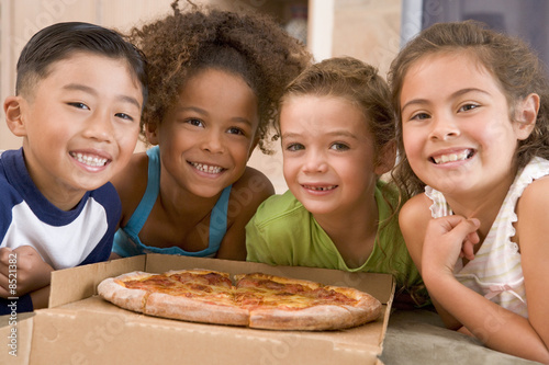 Photo: Four young children with pizza smiling Four young children with pizza smiling