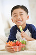 Young boy eating bowl of vegetables smiling