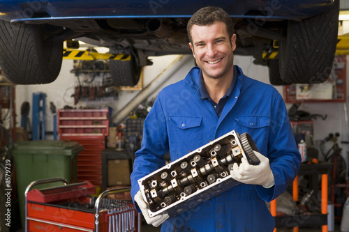 Photo: Mechanic holding car part smiling Mechanic holding car part smiling