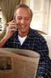 Foto: Mature man reading newspaper and talking on cell phone Mature man reading newspaper and talking on cell phone