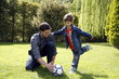 Man teaching boy to play soccer