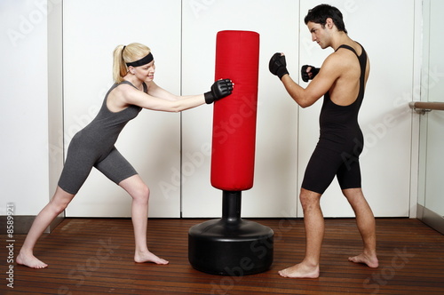 Photo: Young man and woman practicing with a punching bag Young man and woman practicing with a punching bag