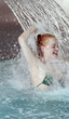 Young woman standing under water spray in spa pool
