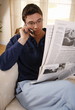 Man reading newspaper and talking on cell phone