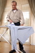 Mature man ironing shirt