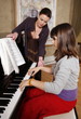 Woman teaching piano to girl