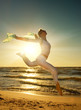 Beautiful young woman jumping on a beach at sunset