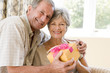 Husband giving wife gift in living room smiling Husband giving wife gift in living room smiling