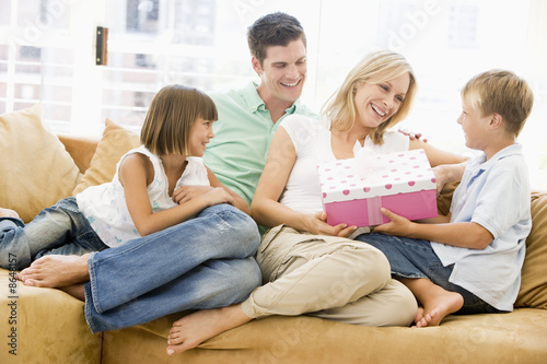Foto: Family in living room with mother receiving gift and smiling Family in living room with mother receiving gift and smiling