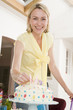 Woman putting candles in cake smiling