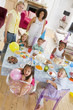 Young children at party with mothers sitting at table with food