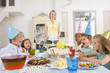 Photo: Young children at party sitting at table with mother carrying ca Young children at party sitting at table with mother carrying ca