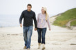 Photo: Couple walking at beach holding hands smiling Couple walking at beach holding hands smiling