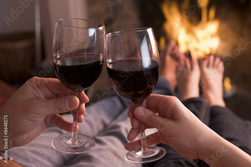 Photo: Feet warming at fireplace with hands holding wine Feet warming at fireplace with hands holding wine